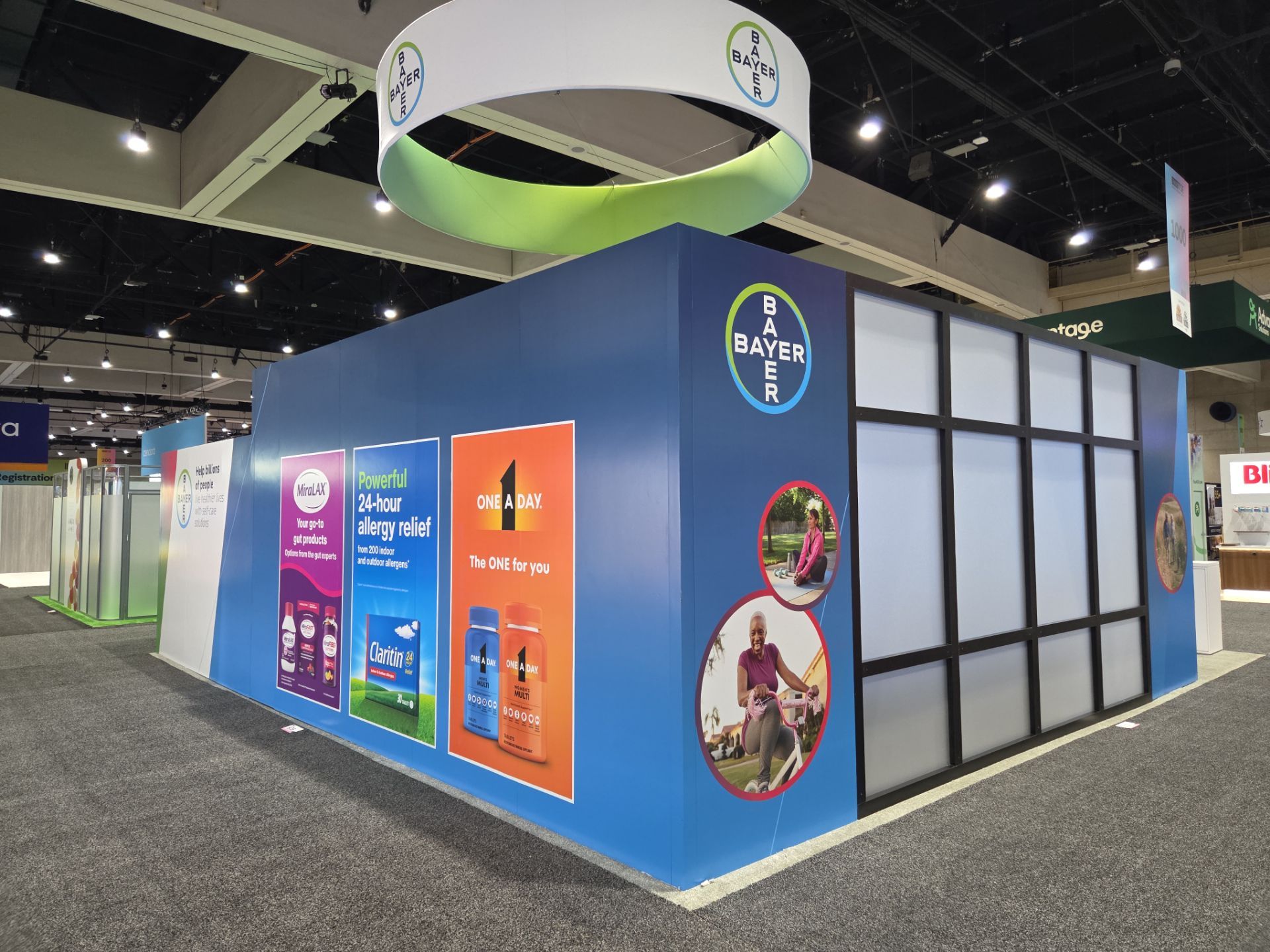 Bayer booth exterior showing brand vignettes on side wall with competitor booths visible